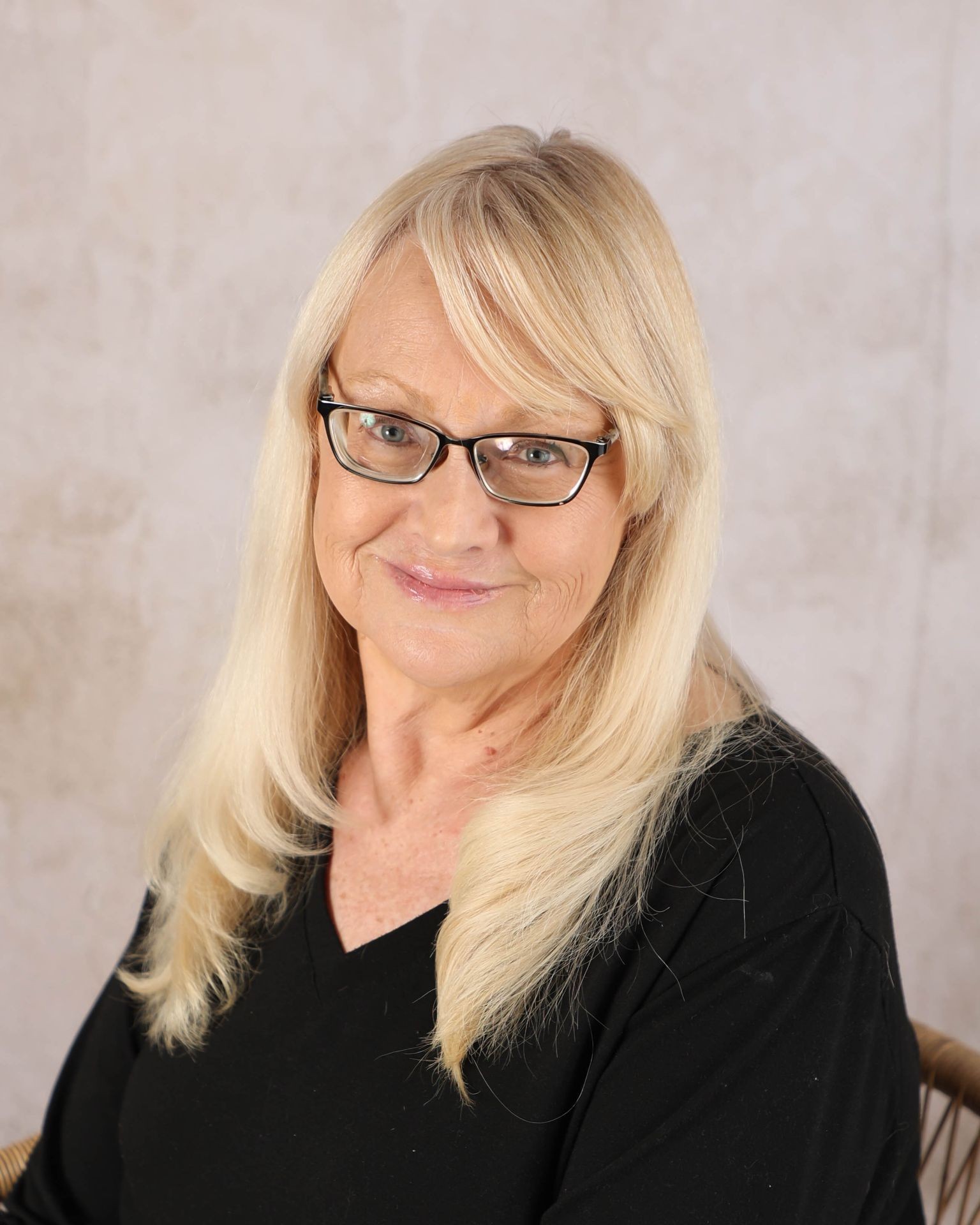 A woman with shoulder-length blonde hair wearing a black top sits against a neutral background.